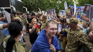 Some women held up pictures of missing relatives as released Ukrainian soldiers returned home. (AP PHOTO)